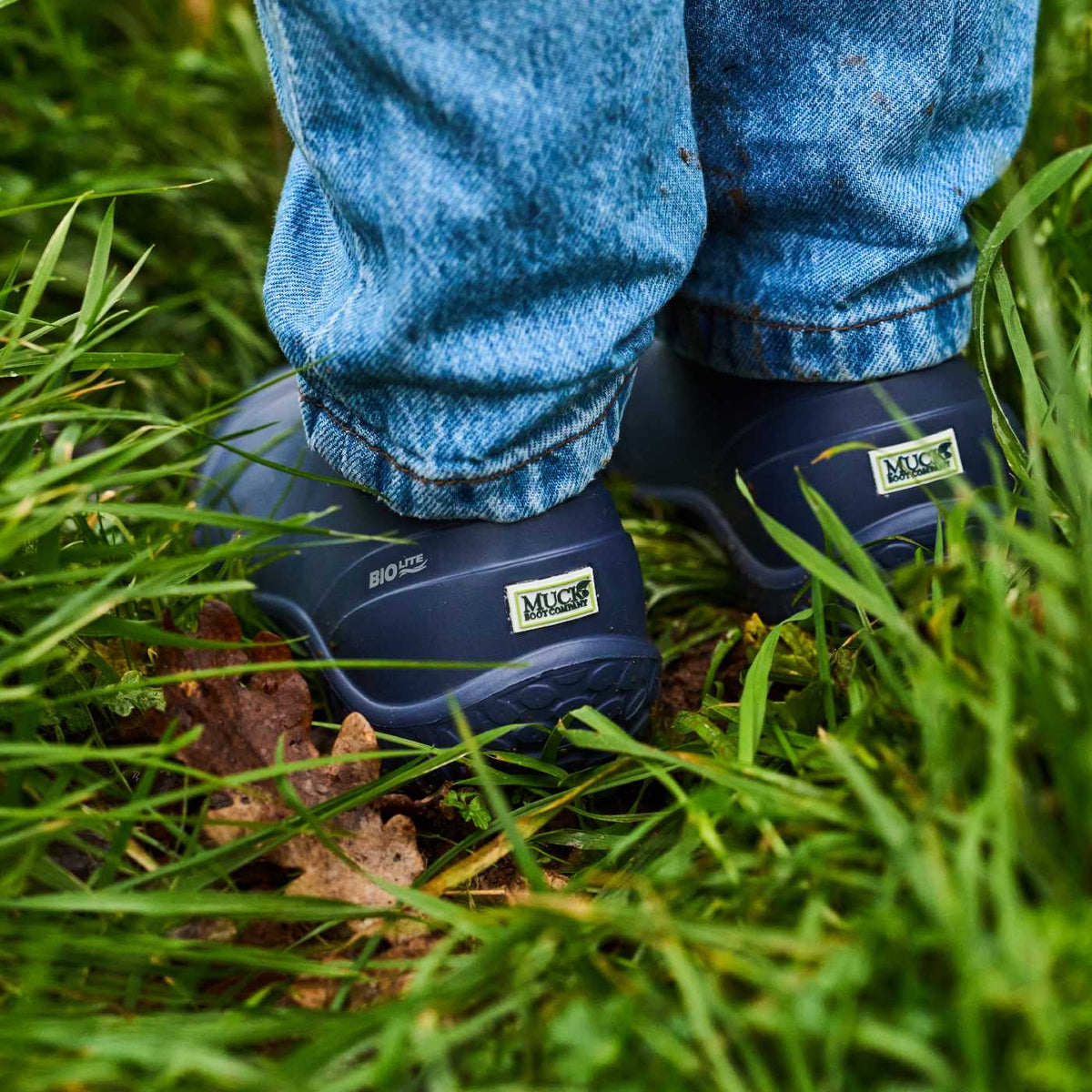 Navy Muck boots worn with blue jeans on grass