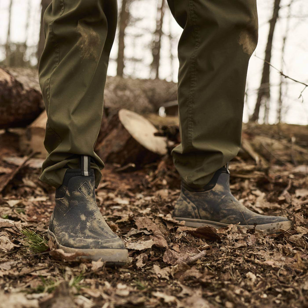 MXP6M00 Person standing on dead leaves wearing Xplorer 6" Men's Waterproof Outdoor Ankle Boots in Black.