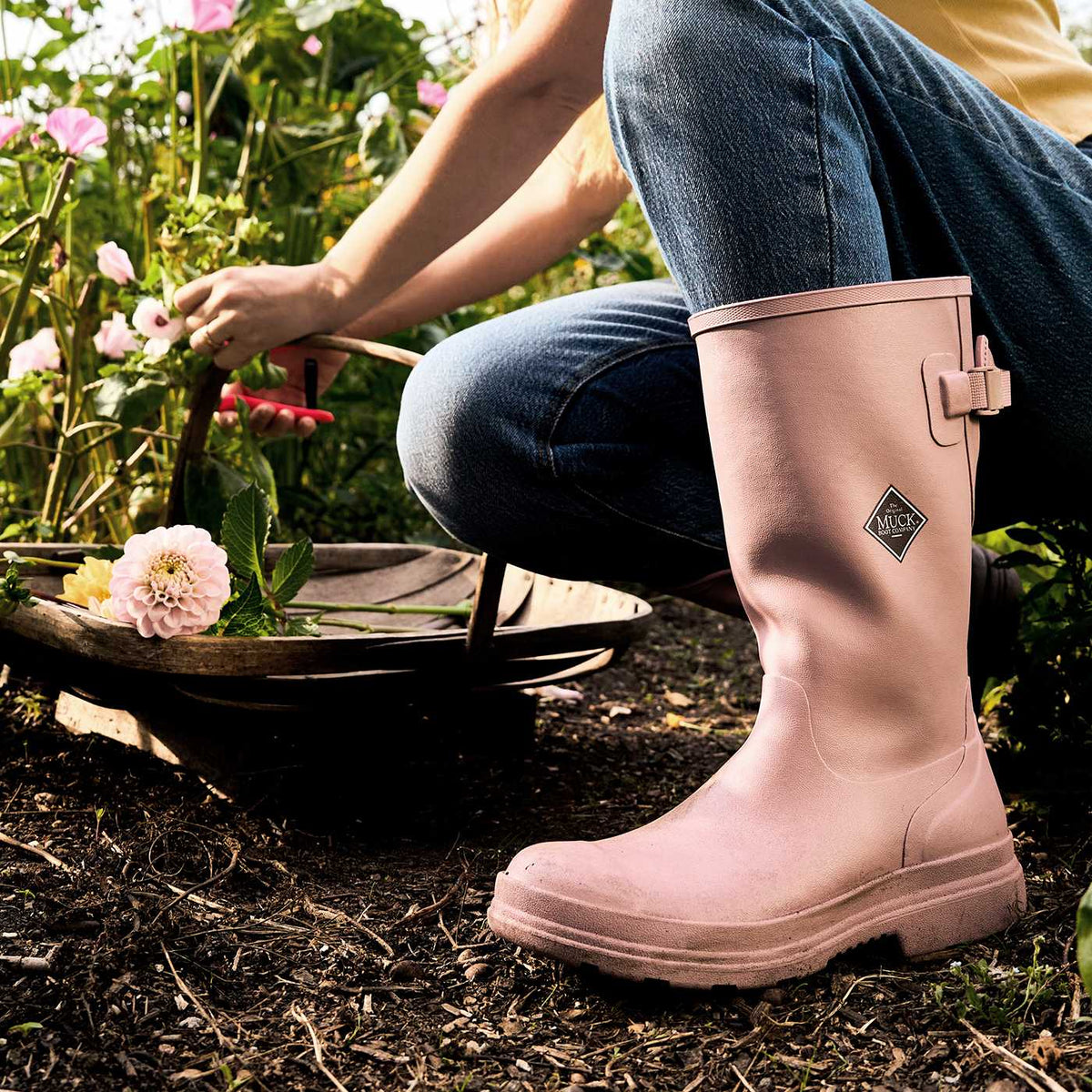 Person wearing pink rubber boots in a garden setting