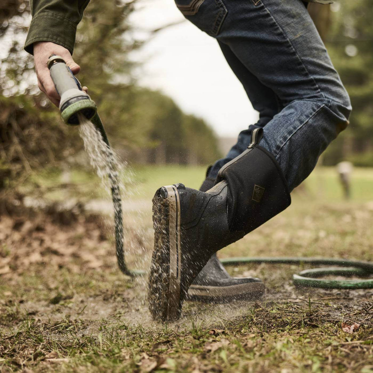 MXP12M00 Person rinsing off Xplorer 12" Men's Waterproof Outdoor Boots with hose showing the outsole.