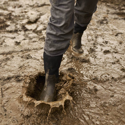 MXP12M00 Person walking through muddy puddle wearing Xplorer 12" Men's Short Outdoor Boots.